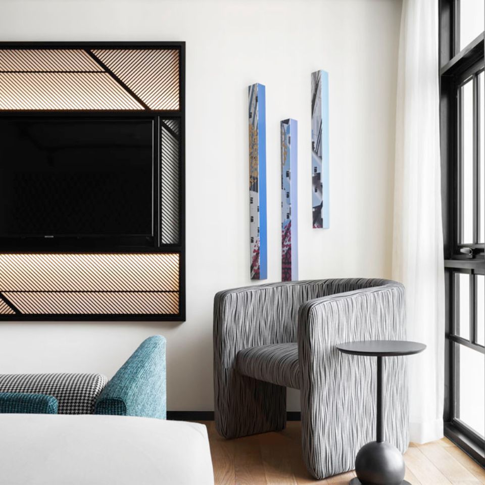 A grey armchair with a small black table next to it. To the left is a black TV screen