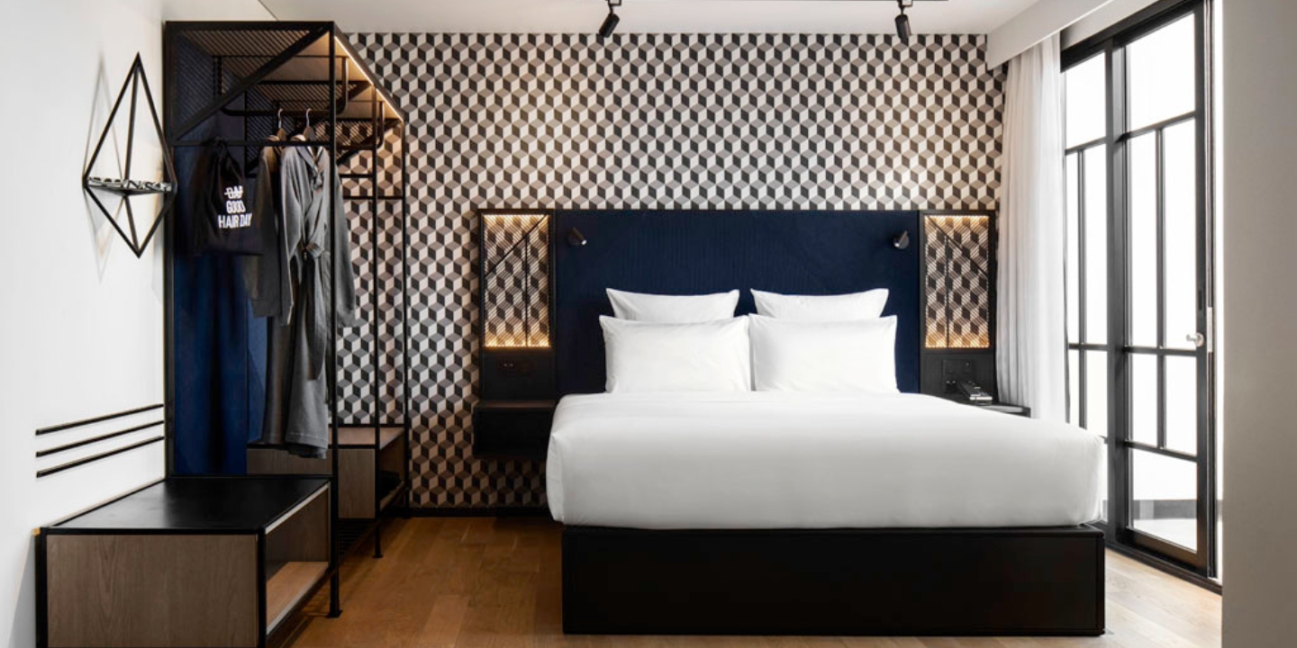 Guest Room with a double bed with white linen, a blue headboard, to the left is a black wardrobe with a grey robe