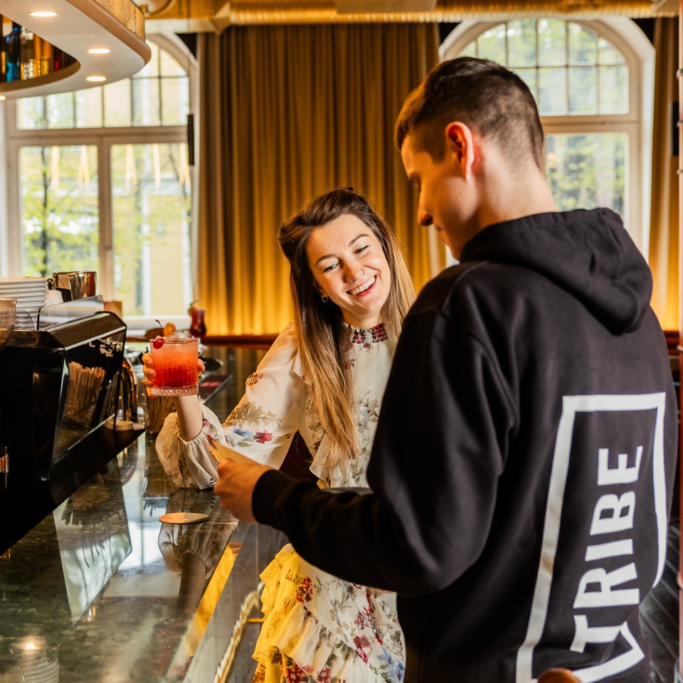 A team member is talking to a guest, who is holding a drink in their hand.