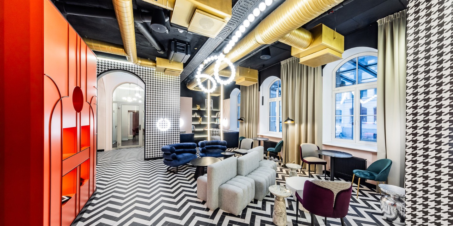 A stylish lounge with bold patterns, modern furnishings, and bright decor, featuring a zigzag floor and golden accents.