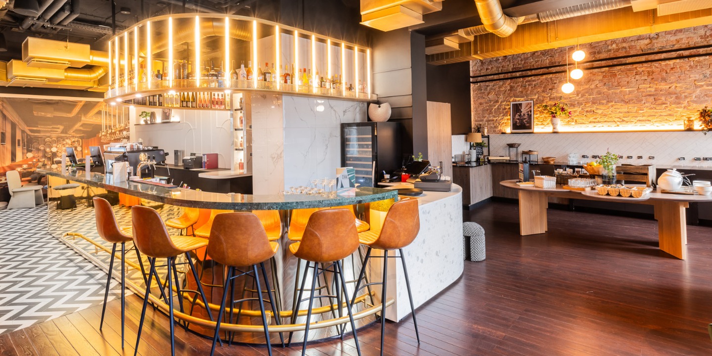 Stylish bar area featuring high stools, a sleek counter with beverages, and a cozy seating arrangement in a contemporary setting.