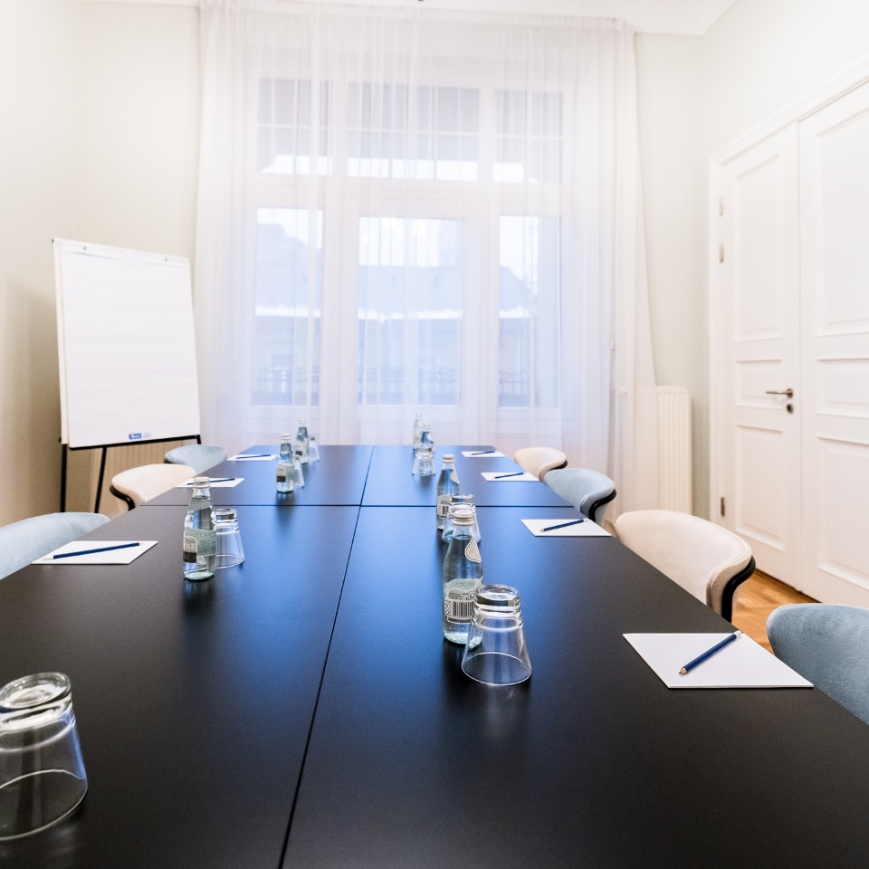 A conference table with water bottles, notepads, and a blue pencil, alongside stylish chairs, set for a meeting.