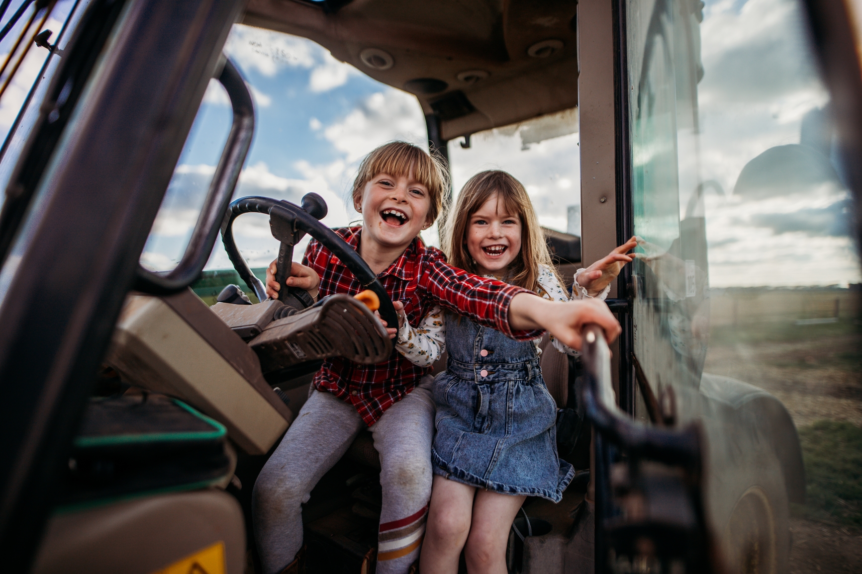 two girls in a tractor cab laughing